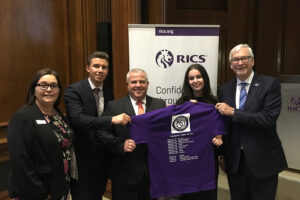 The team presenting a T-Shirt at the Head Office of the Royal Institution of Chartered Surveyors at Parliament Square, London